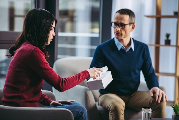 Psychologue masculin donnant une serviette à une femme bouleversée dans le cabinet du médecin