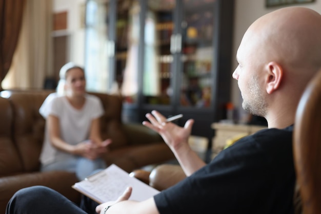Le psychologue parle au patient assis sur une chaise au bureau pendant la psychothérapie