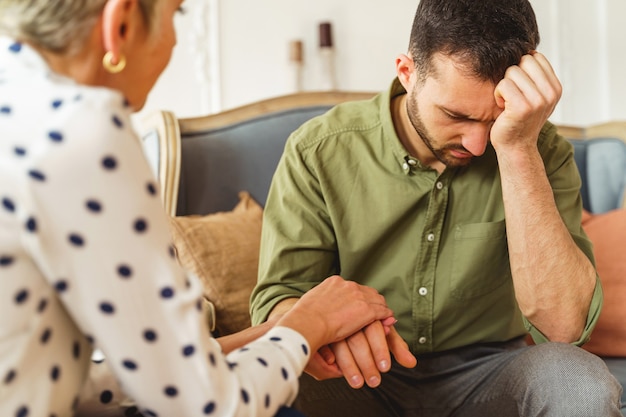 Psychothérapeute senior offrant une assistance professionnelle à un jeune homme souffrant pendant la séance de thérapie