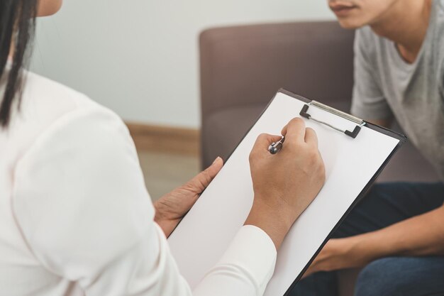 Psychothérapie jeune psychologue femme consulter, prendre des notes avec un homme asiatique a des symptômes mentaux, le stress s'asseoir sur le canapé pendant le traitement de diagnostic du thérapeute. Psychologie, médecin ou concept médical.