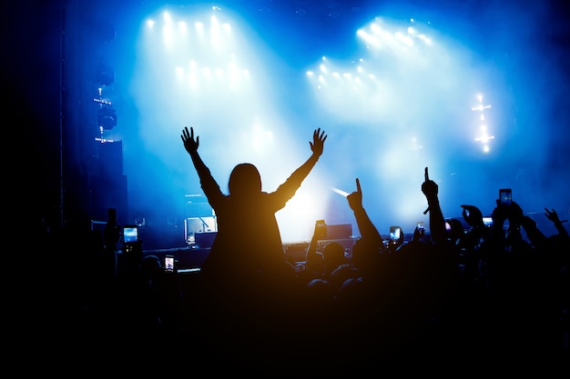 Le public du concert apprécie. Silhouettes de mains levées et de smartphones.