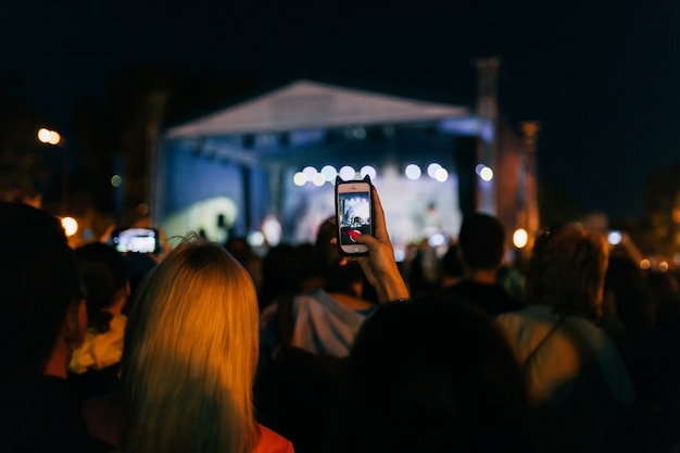 Public enregistre une vidéo et prend des photos d'un groupe sur son téléphone portable en concert