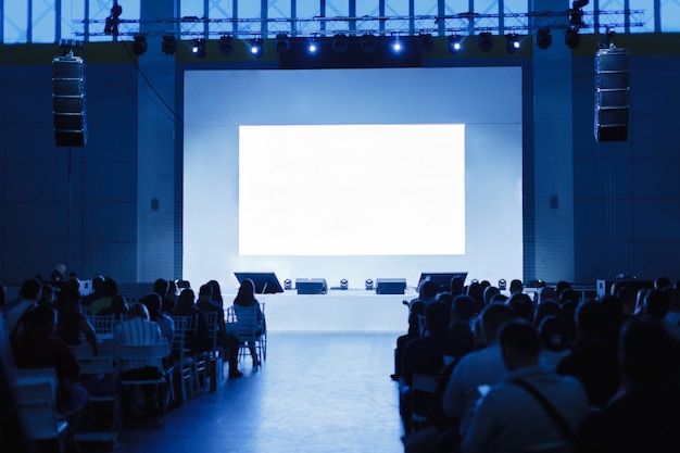 Public à la salle de conférence. se concentrer sur la scène. Les gens attendent l'orateur. photo teintée bleu