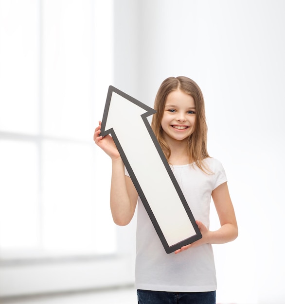 publicité et concept d'enfant - petite fille souriante avec une flèche vide pointant vers le haut