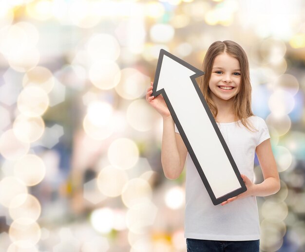 publicité et concept d'enfant - petite fille souriante avec une flèche vide pointant vers le haut