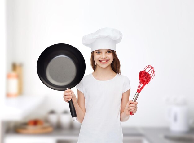 publicité, enfance, cuisine et personnes - jeune fille souriante en t-shirt blanc et chapeau de cuisine tenant une casserole sur fond bleu