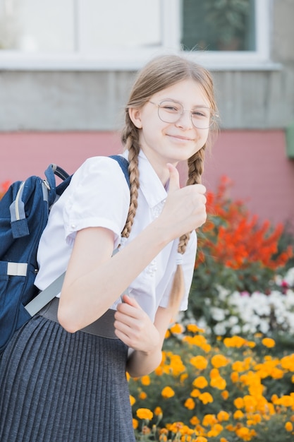 La publicité des produits. Joyeux petit enfant d'âge scolaire présentant votre produit. Petite fille avec des livres souriant et présentant un produit ou un service. Vous ne pouvez jamais vous tromper avec ce produit.