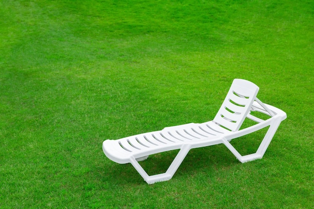 Photo publicité récréative et touristique chaise ou chaise longue en plastique vide sur l'herbe d'une pelouse fraîche