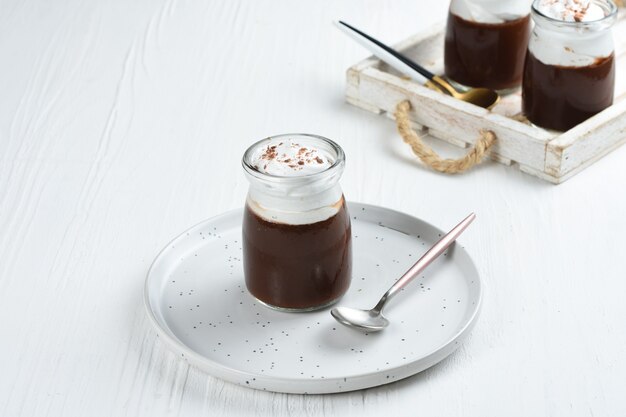 pudding au chocolat avec crème fouettée et chocolat comme garniture dans des verres à portion