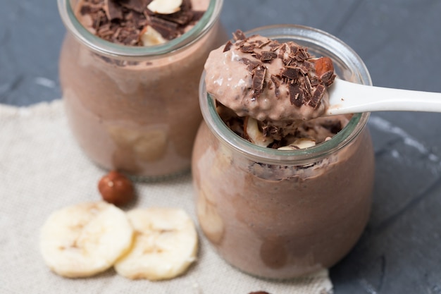 Pudding au chocolat avec graines de chia, bananes et noix, dans un bocal en verre