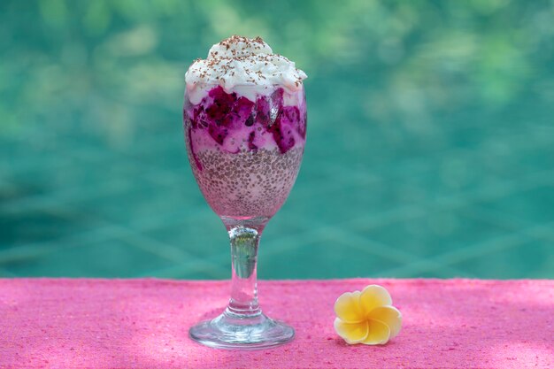 Pudding aux graines de chia avec fruit du dragon rouge et yaourt blanc dans un verre pour le petit-déjeuner sur le fond de l'eau de la piscine, gros plan. Le concept d'une alimentation saine.