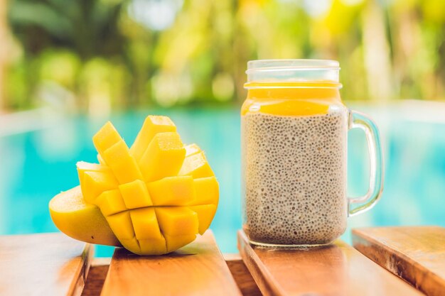 Pudding aux graines de chia avec lait d'amande et garniture de mangue fraîche sur le fond de la piscine