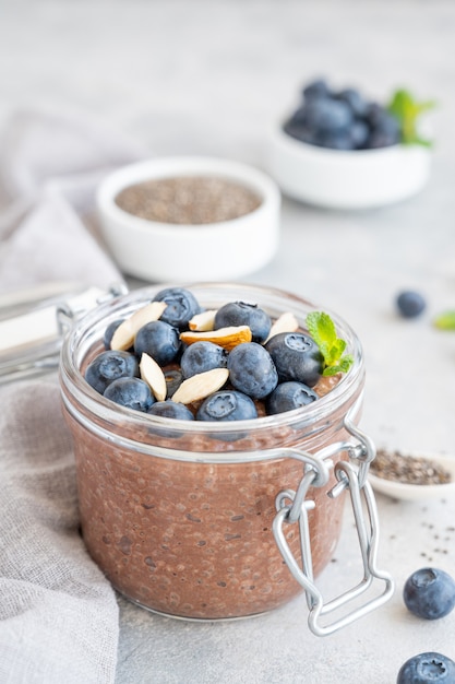 pudding de chia au chocolat avec myrtille, amandes et menthe sur le dessus dans un bocal en verre