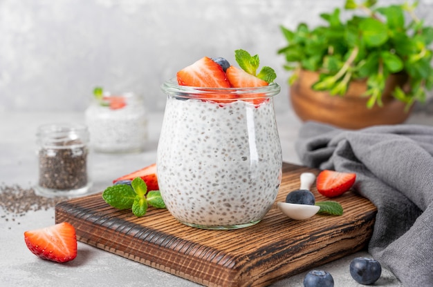 Pudding de chia avec fraise fraîche et myrtille sur le dessus dans un bocal en verre.