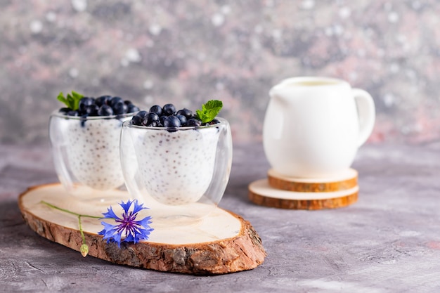 Pudding de chia à la menthe et myrtilles dans des verres sur un support en bois