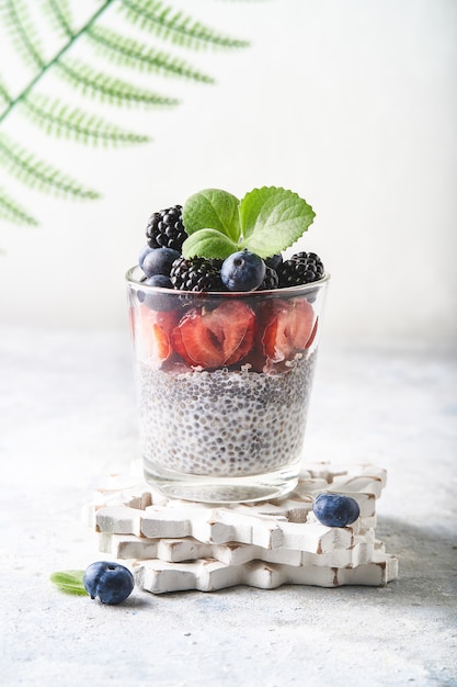 Pudding de chia sain avec des fraises, des mûres, des myrtilles et des figues servi dans un verre