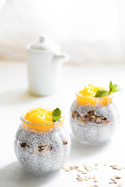 Pudding de chia sain avec granola de graines de chia à la mangue et au lait de coco dans un concept en verre d'une alimentation saine