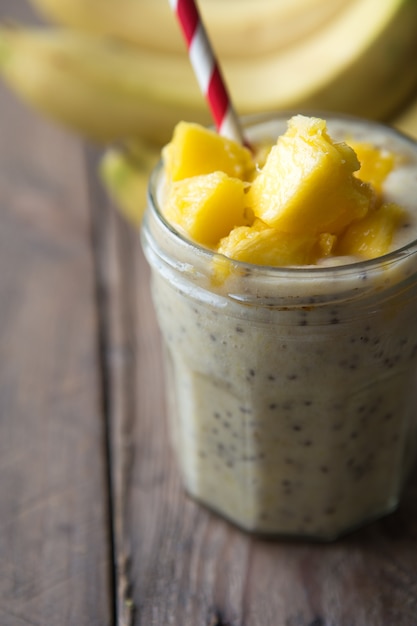 Photo pudding à la mangue chia en pot de verre mangue, banane, menthe sur fond blanc - superaliments sains végétaliens, petit-déjeuner sans produits laitiers