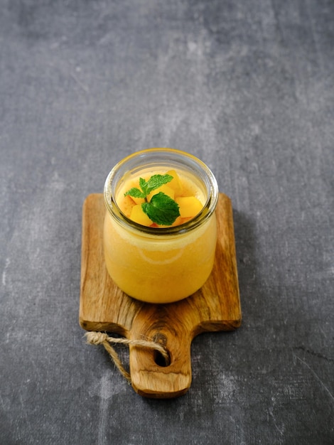 Pudding à la mangue garni d'une tranche de mangue et d'une garniture de feuilles de menthe. Servi dans un bocal