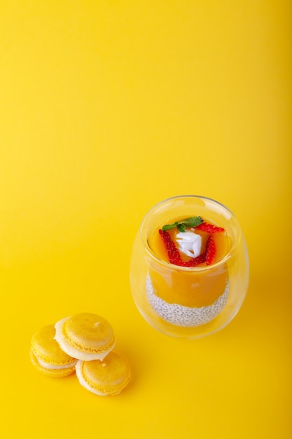 Pudding à la mangue avec des graines de chia en verre sur fond jaune