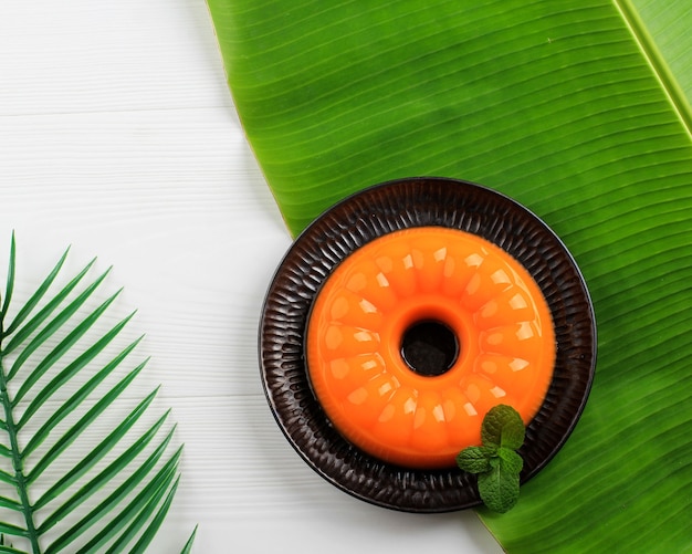 Pudding à la mangue pour un été frais. Servir au-dessus de la feuille de bananier, assiette noire