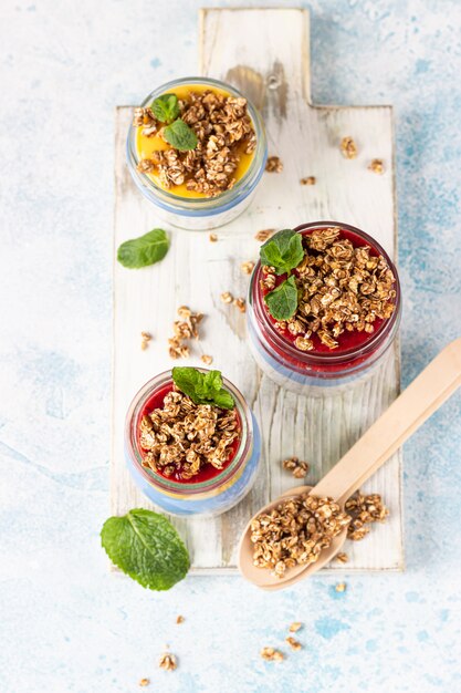 Puddings chia à la spiruline bleu vegan avec confiture et granola dans des bocaux en verre