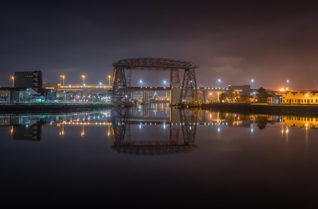 Photo puente transbordador sur la rivière matanuska par la ville éclairée contre le ciel la nuit