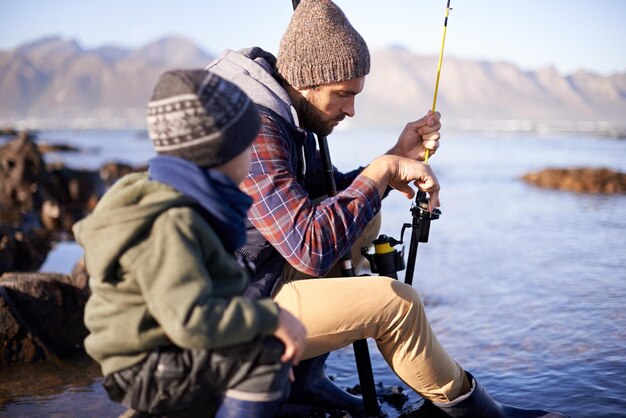 Et puis tu retournes ça ici Photo d'un mignon petit garçon pêchant avec son père au bord de la mer