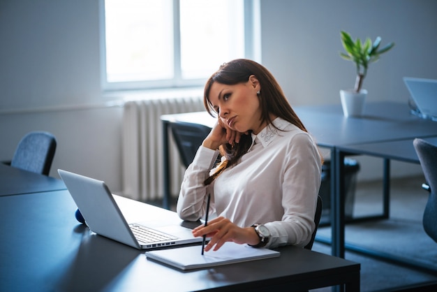 Épuisé femme assise devant un ordinateur