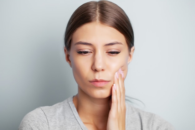 Épuisé jeune femme souffrant de maux de dents sévères