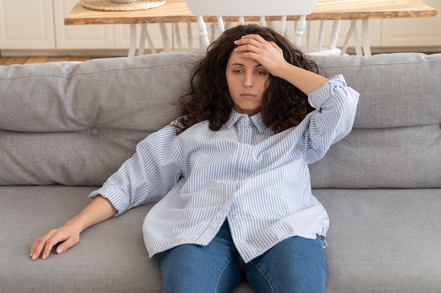 Épuisé, une jeune femme stressée allongée sur un canapé à la maison se sent dépassée