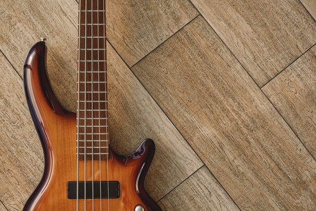 Puissance de l'instrument de musique. Vue de dessus de la guitare électrique brune allongée sur le plancher en bois. Matériel de musique. Instruments de musique. Notion musicale