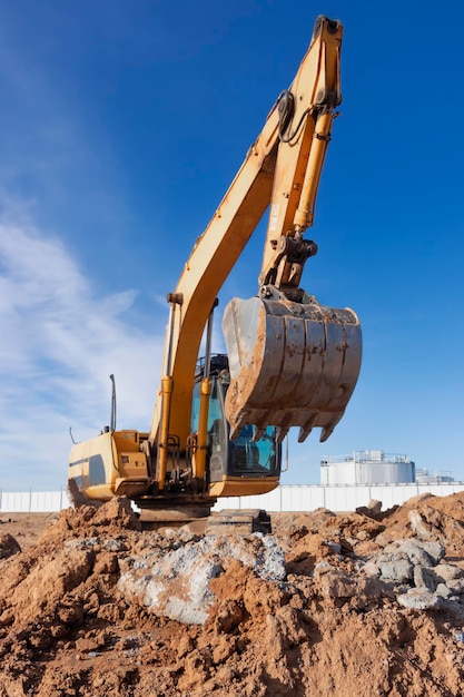 Une puissante excavatrice à chenilles creuse le sol contre le ciel bleu Travaux de terrassement avec de l'équipement lourd sur le chantier de construction