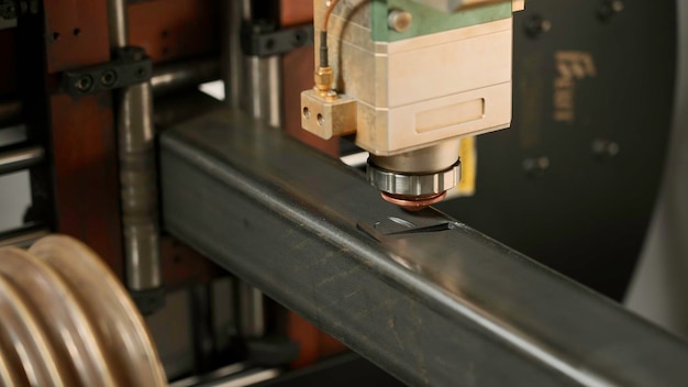 Une puissante machine laser coupe des pièces d'un métal épais en créant des détails de découpe au laser.