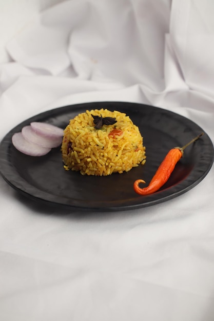 Pulao de biryani végétarien décoré dans un bol noir sur un tissu blanc, à base de riz et de fruits secs