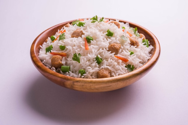 Pulao de soja nutritif ou pilaf ou riz frit en morceaux de soja avec des pois verts et des haricots. Servi dans un bol sur fond coloré ou en bois. Mise au point sélective