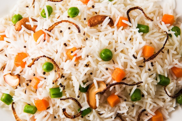 Pulav indien ou biryani végétarien à base de riz basmati servi dans une assiette en céramique blanche, mise au point sélective