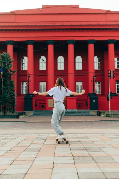 Pull femme verticale se promener dans la ville sur un longboard