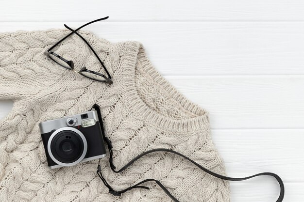 Pull d'hiver gris pour femmes, appareil photo instantané et lunettes sur fond de bois blanc