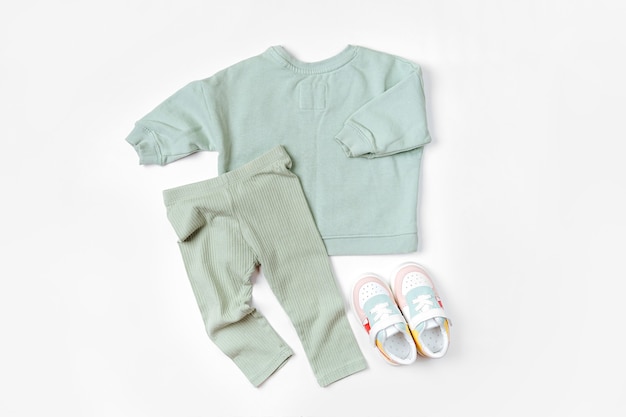 Pull et pantalon avec baskets. Ensemble de vêtements et accessoires pour bébé pour le printemps, l'automne ou l'été sur fond blanc. Tenue de mode pour enfants. Mise à plat, vue de dessus