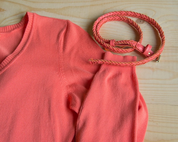 Pull rose mode femme avec ceinture sur fond bois clair
