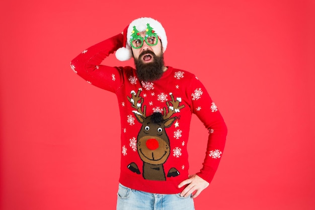 Pull en tricot Bonne année Esprit de Noël Tenue de fête d'hiver Pull avec cerf Magasin de vêtements Acheter des vêtements de fête Accessoires de vacances Hipster barbu porte un pull et un chapeau d'hiver