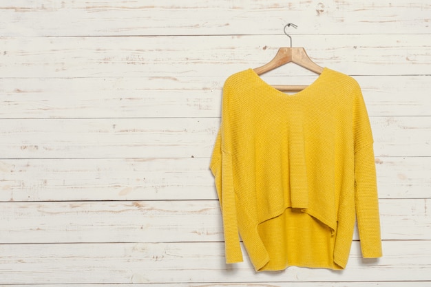 Pull en tricot sur un portant en bois