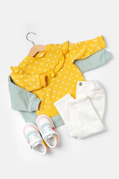 Photo pulls sur cintre et pantalon avec baskets. ensemble de vêtements et accessoires pour bébé pour le printemps, l'automne ou l'été sur fond blanc. tenue de mode pour enfants. mise à plat, vue de dessus