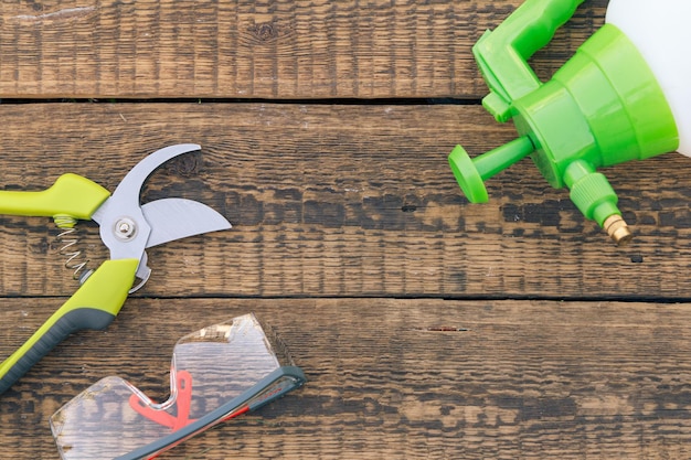 Pulvérisateur à pression sécateur et lunettes de protection sur planche de bois Outils et équipement de jardin Vue de dessus