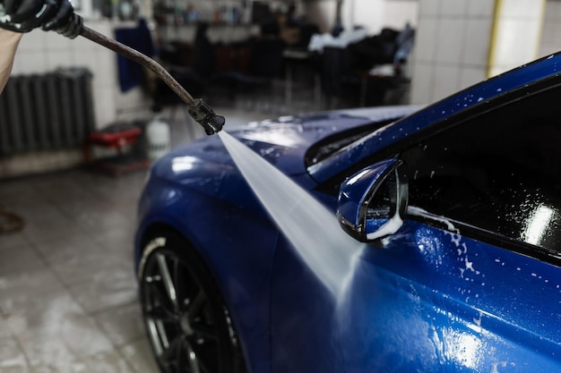 Pulvériser de l'eau sur la voiture pour laver la mousse dans le garage