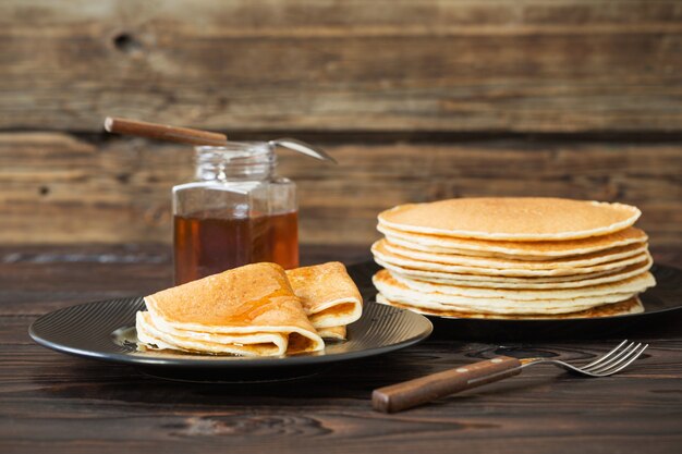 Puncakes au miel et tasse de thé sur le vieux mur en bois