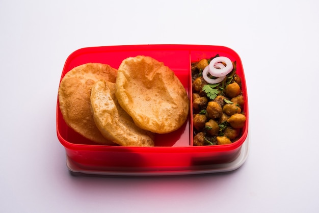 Punjabi Chole ou Choley masala avec puri ou poori dans une boîte à lunch ou un tiffin, mise au point sélective