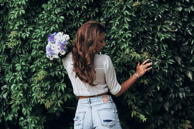 Pur comme la nature. Vue arrière d'une jeune femme séduisante tenant un bouquet en se tenant debout à l'extérieur