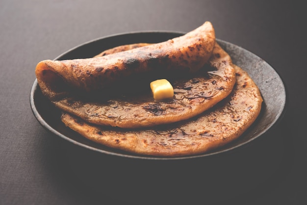 Photo puran poli, également connu sous le nom de holige, est un pain plat sucré indien consommé principalement pendant le festival holi. servi dans une assiette avec du ghee pur sur fond coloré ou en bois